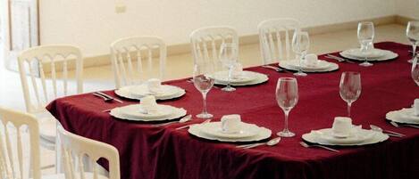 A dining room with a table set for six, white chairs, and a red tablecloth.