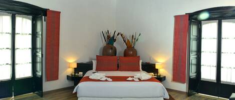 A bedroom with a large bed, two nightstands, two lamps, and two vases on the headboard.