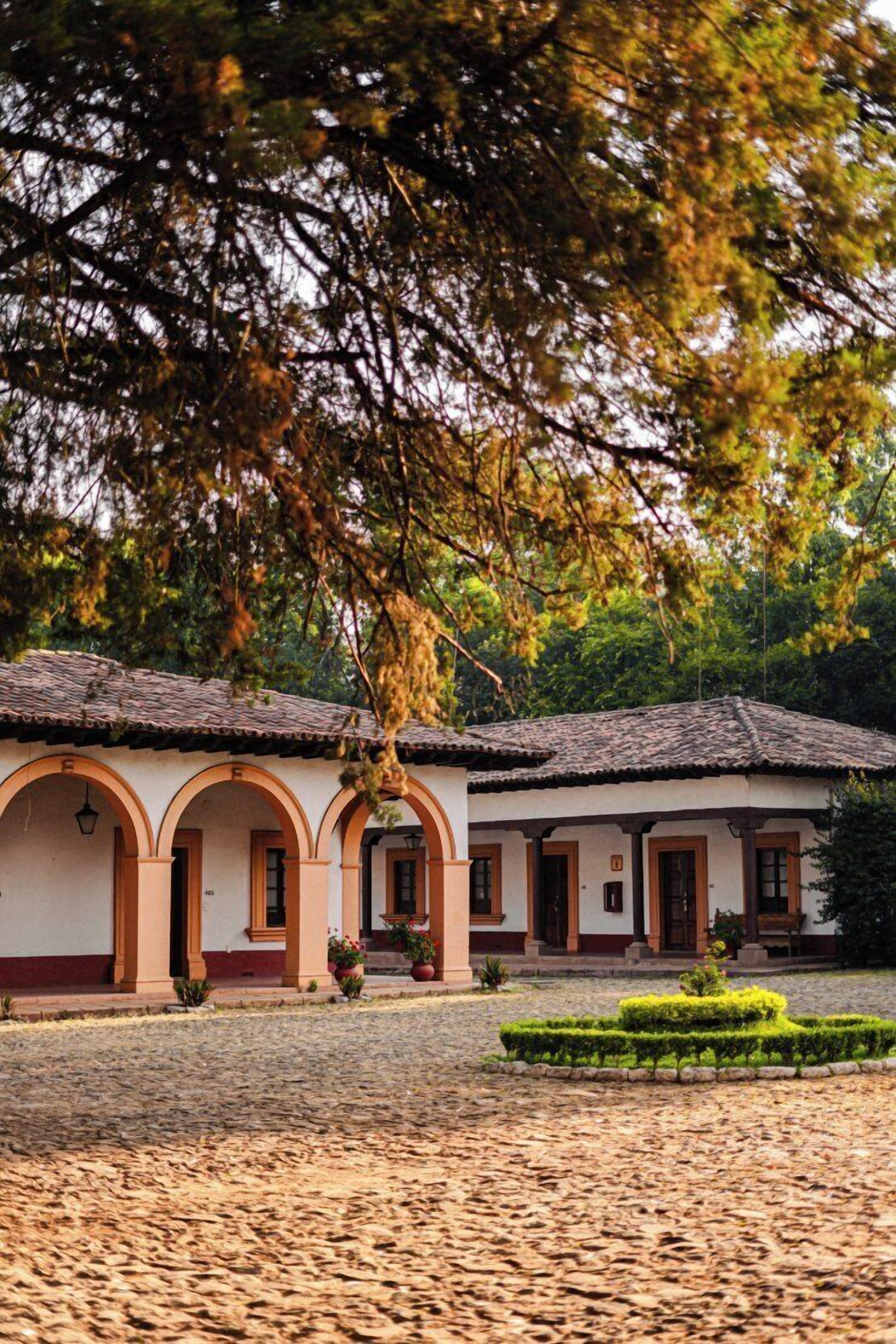 Un edificio con tetto in tegole, portali ad arco e un cortile in pietra.