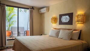 Ein Hotelzimmer mit Bett, einem Fenster mit Vorhängen, einer Wandklimaanlage und zwei Wandleuchten.