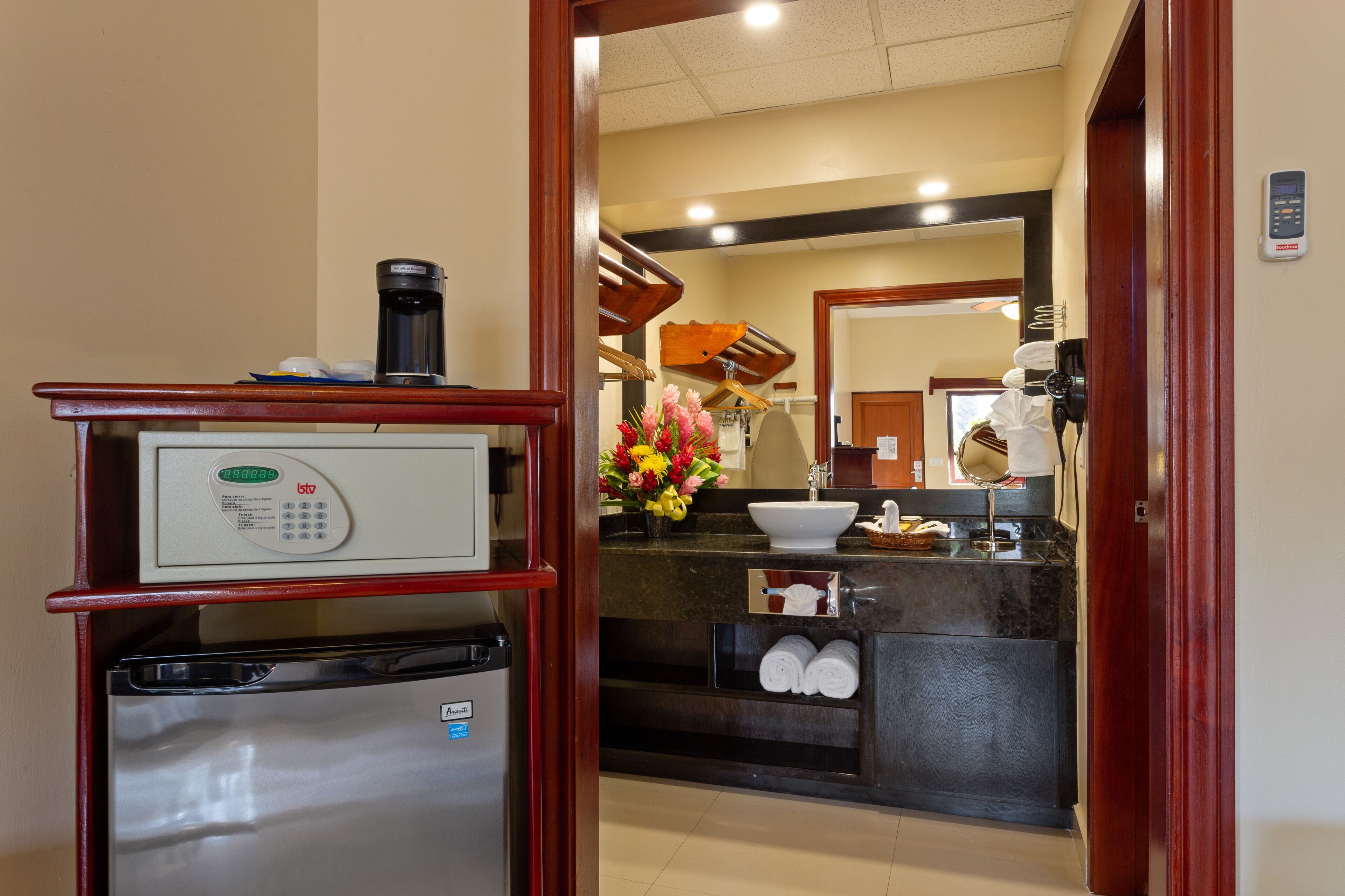 Une chambre d’hôtel équipée d’un mini-bar, d’une machine à café, d’un lavabo et d’un miroir.