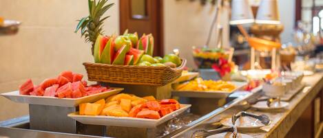 Un bufé con diversas frutas y postres.