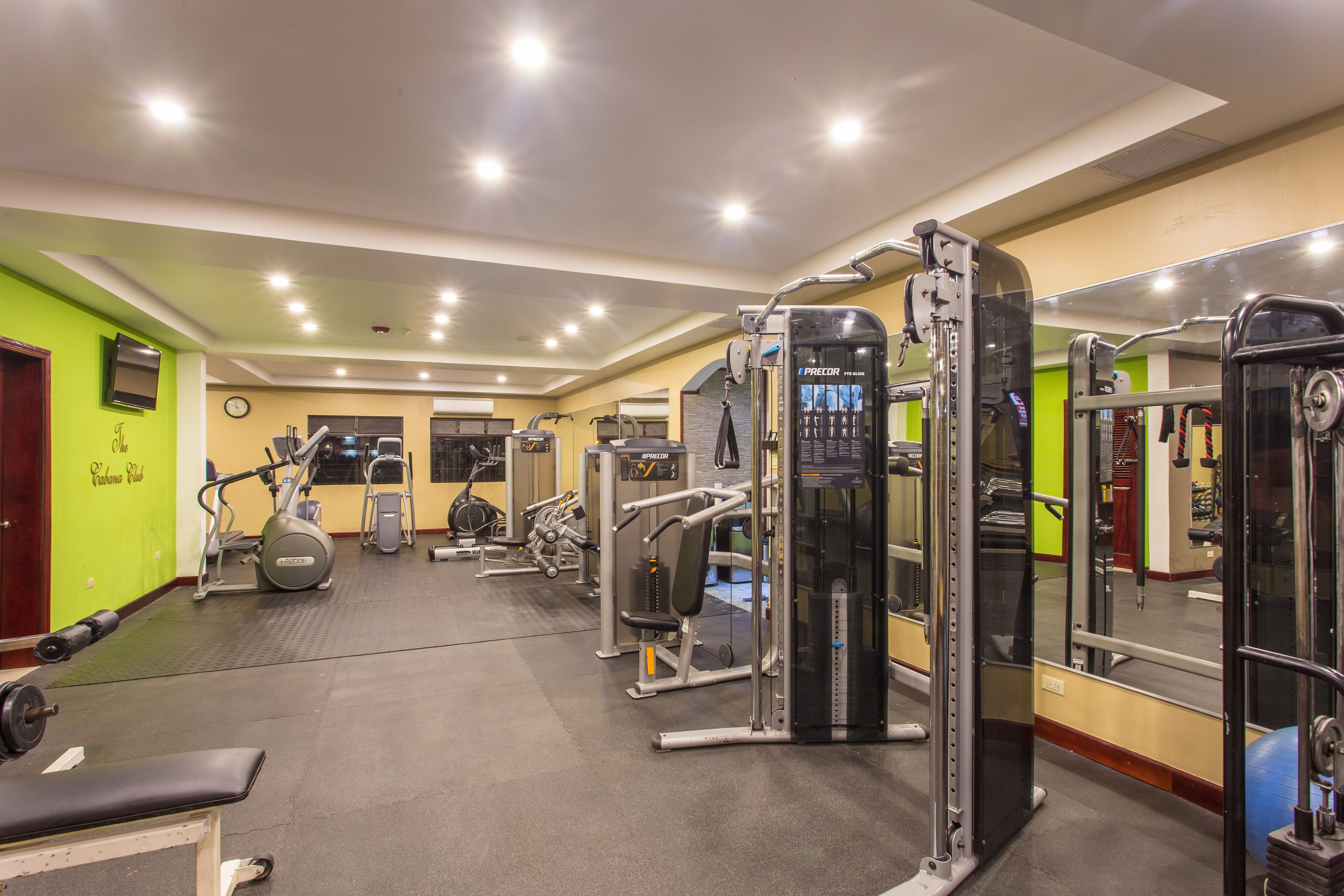 A gym with various exercise machines, a bench, and a mirrored wall.