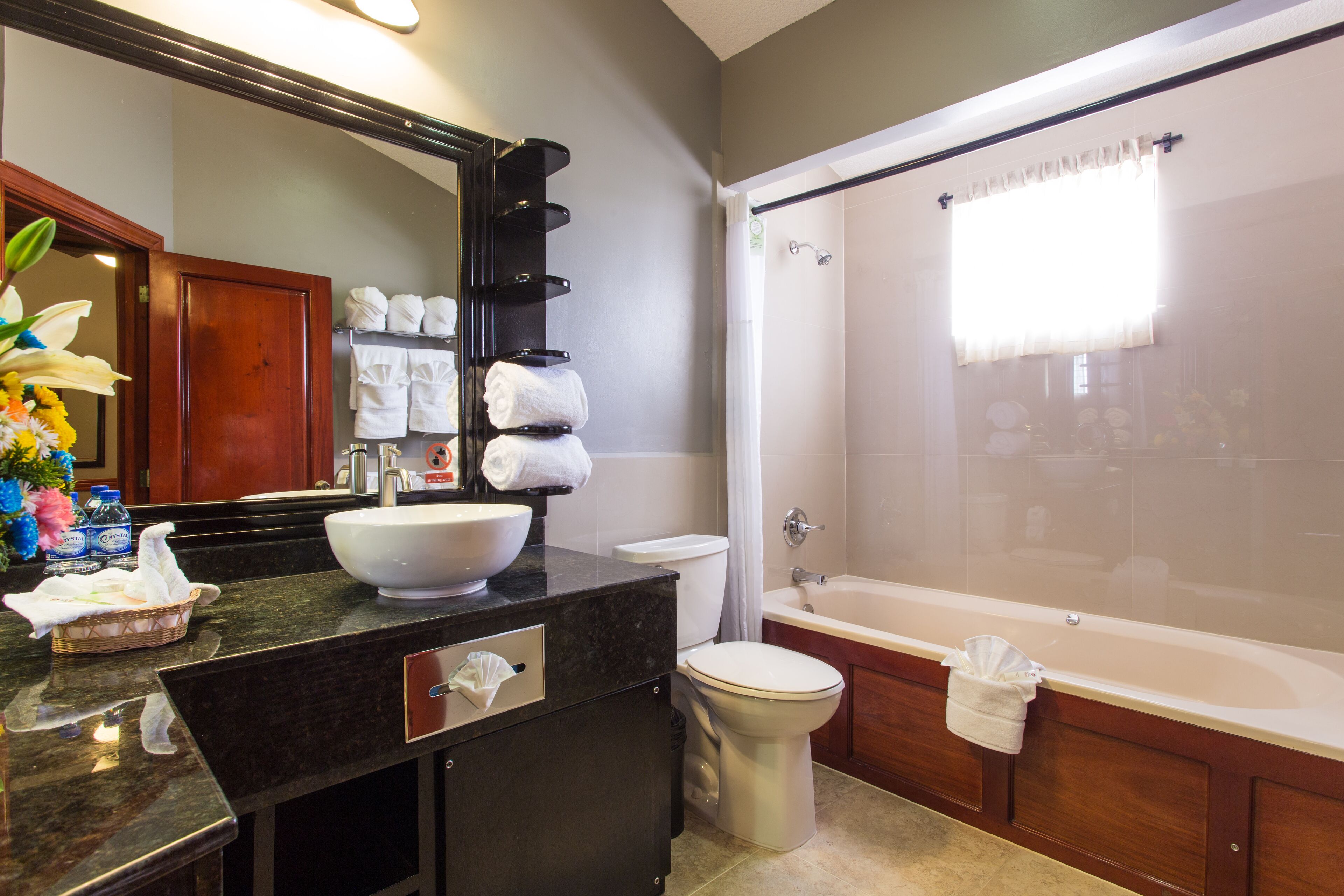 A bathroom with a large sink, toilet, and bathtub. There are towels and toiletries on the counter.