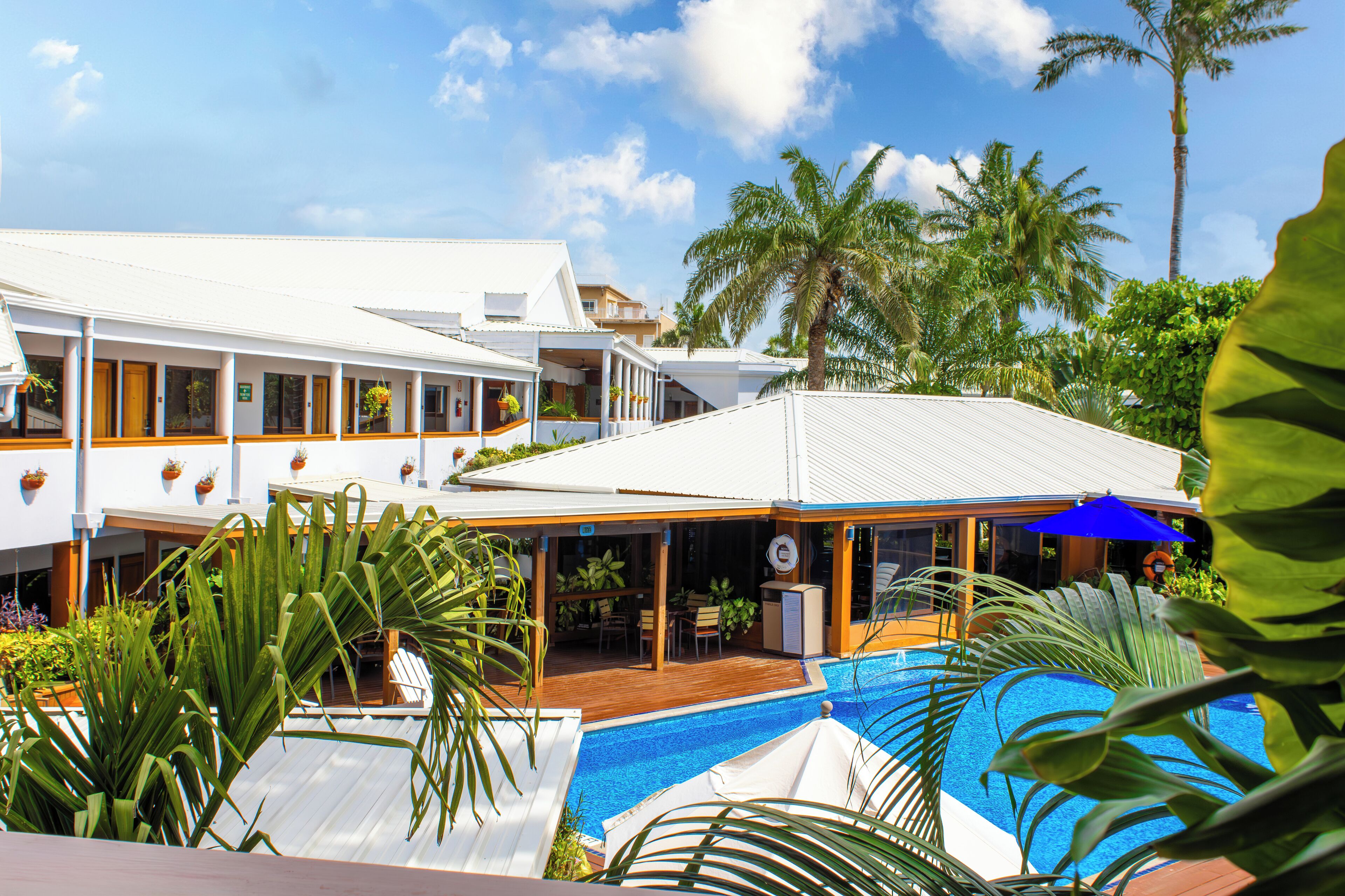 A resort with a swimming pool, covered outdoor seating, and palm trees.