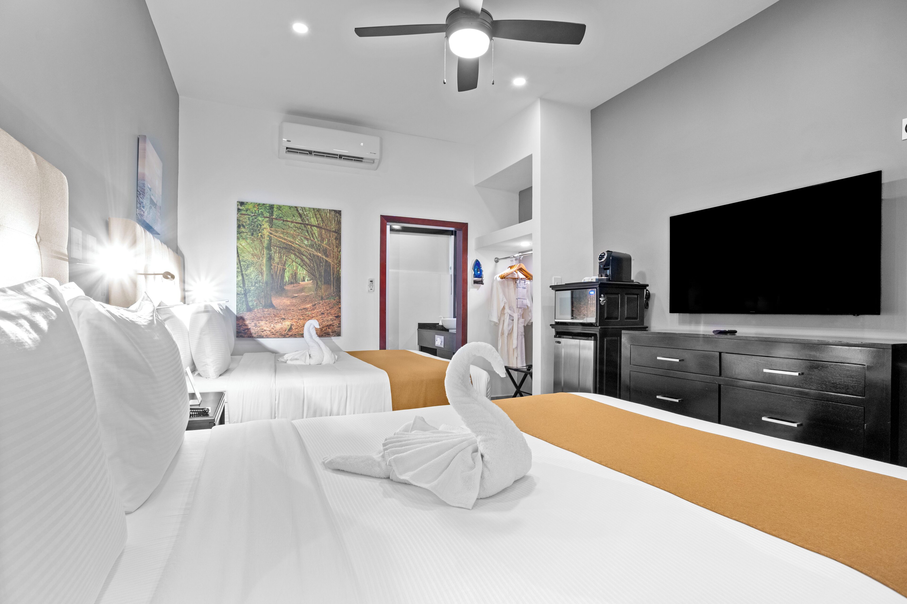 A hotel room with two beds, a flat-screen TV, a wardrobe, and a painting on the wall.