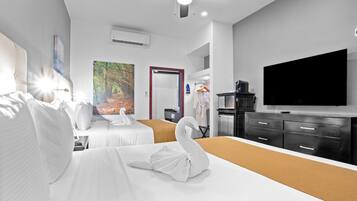 A hotel room with two beds, a flat-screen TV, a wardrobe, and a painting on the wall.