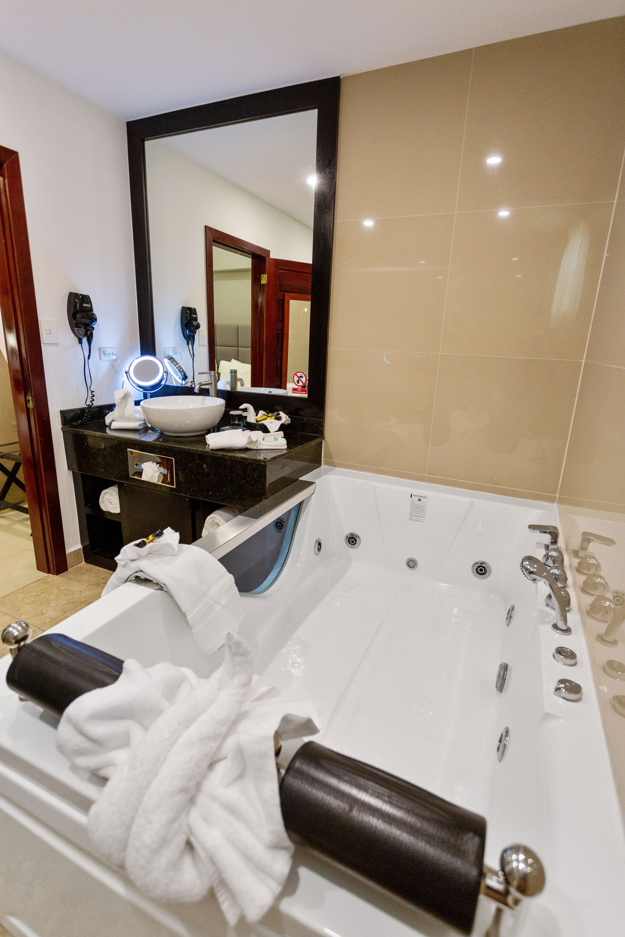 A modern bathroom with a large bathtub, a vanity with a mirror, and a sink.