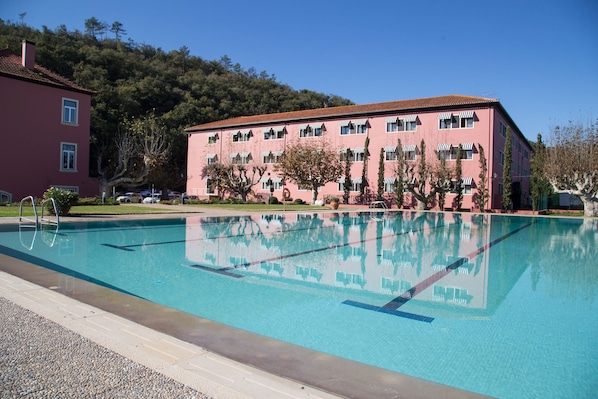 Una piscina al aire libre de temporada, sombrillas