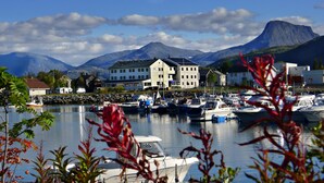 A marina with boats, a large white building, and mountains in the background. - Reisafjord Hotel (Nordreisa)