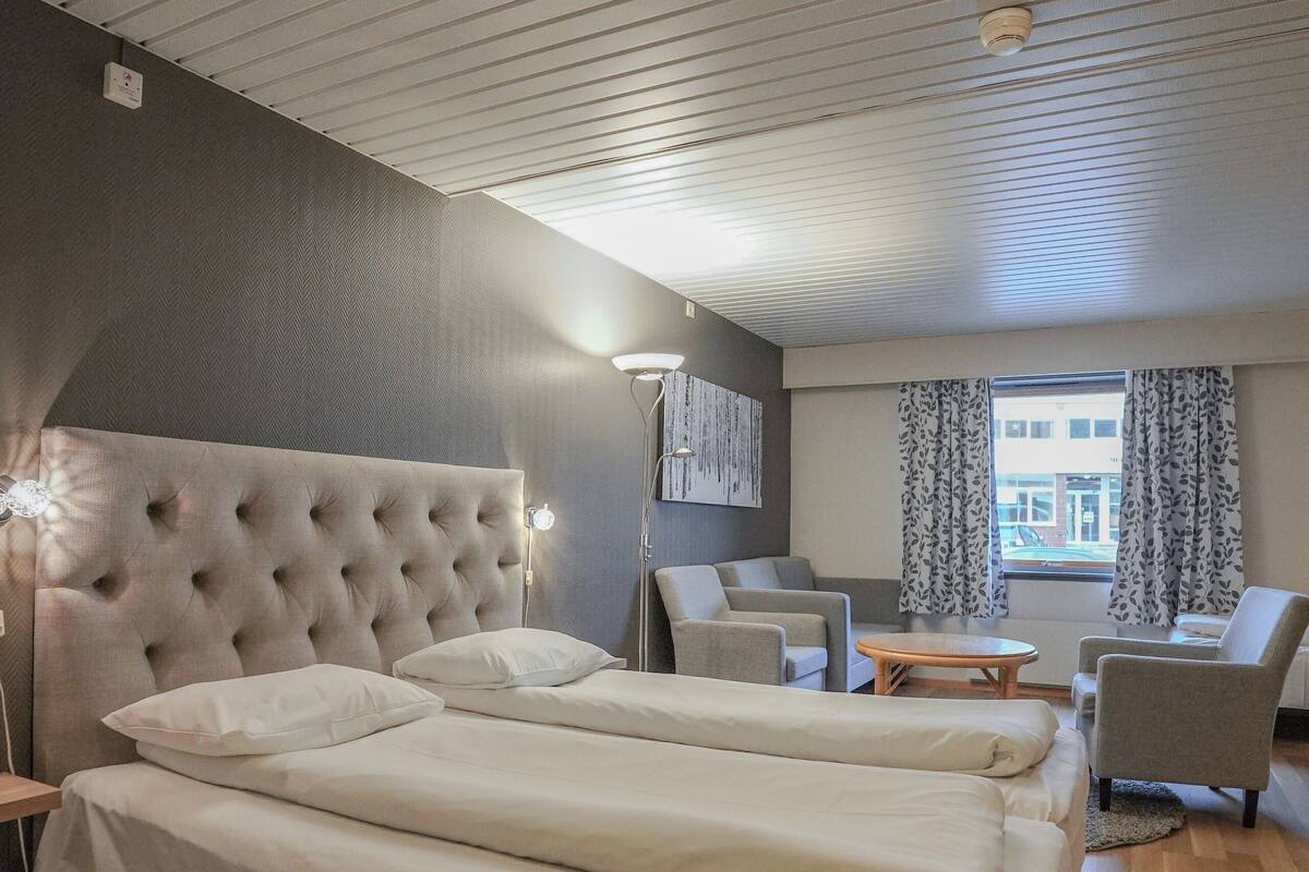 A hotel room with a large bed, two bedside tables, a desk, and a chair.