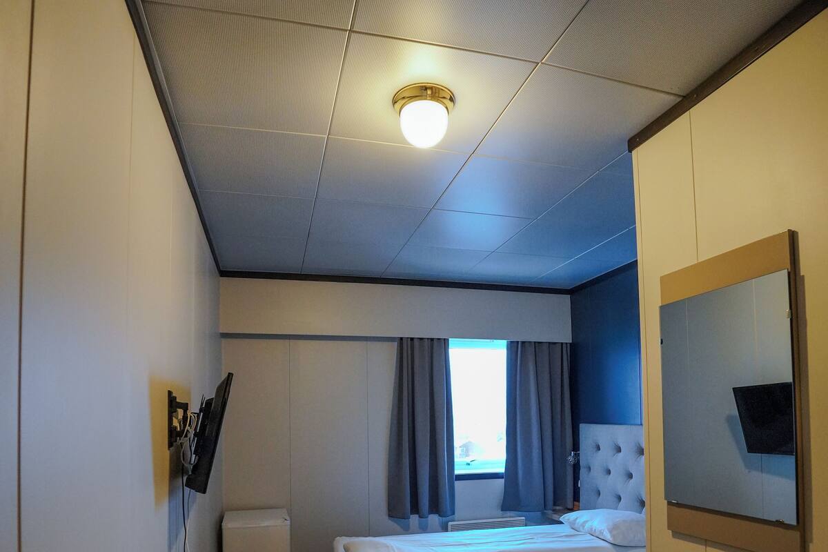 A hotel room with a bed, a desk, a chair, a television, and a window with curtains.