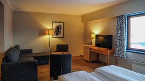 A hotel room with a bed, a desk with a TV, a sofa, and a chair. - Reisafjord Hotel (Nordreisa)