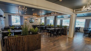 A spacious restaurant with wooden flooring, black chairs, and chandeliers. - Reisafjord Hotel (Nordreisa)