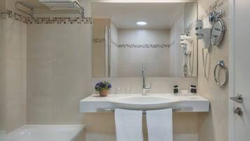 Un bagno moderno con un lavandino capiente, uno specchio, una doccia e un portasciugamani.