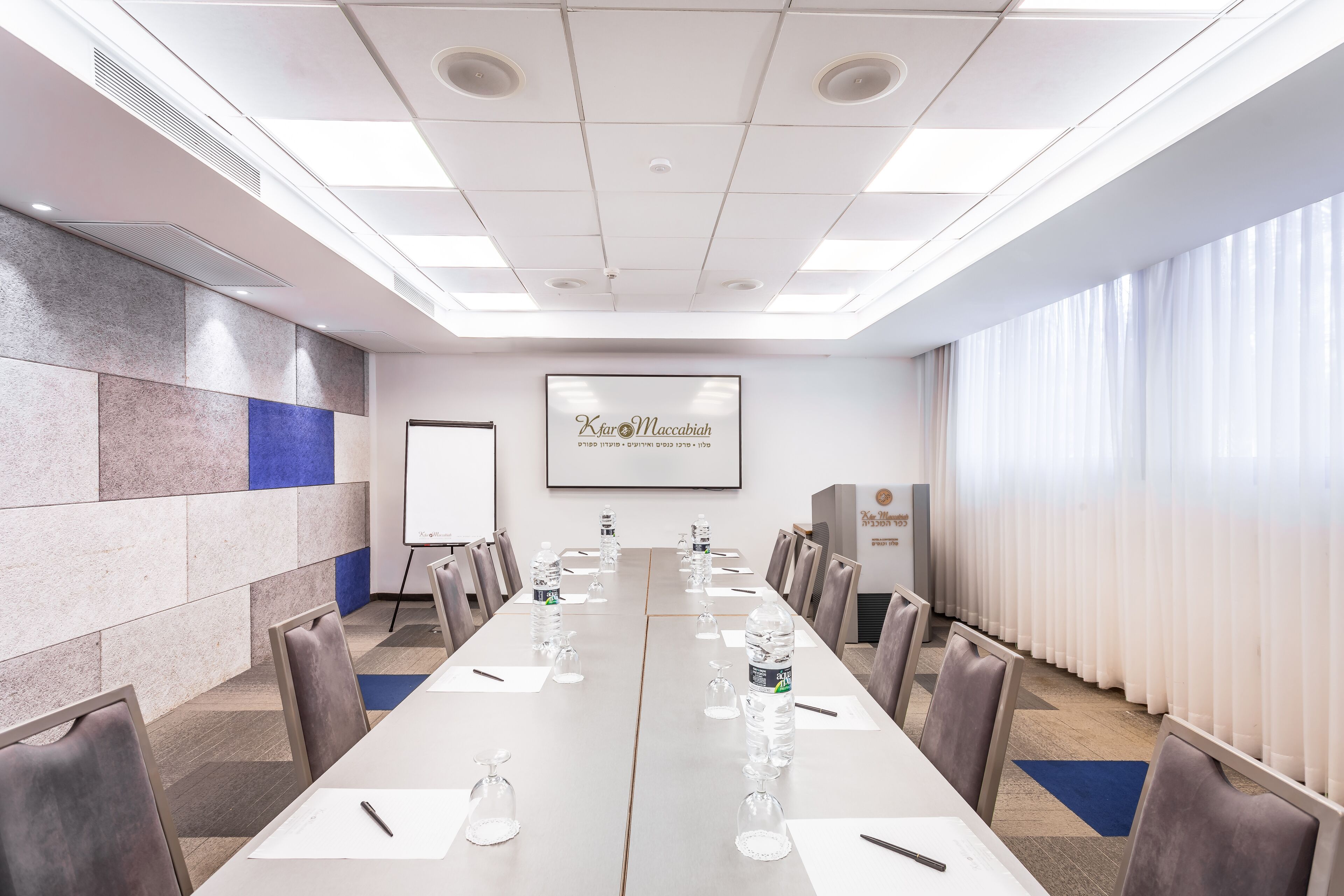 A conference room with a long table, chairs, a projector screen, and a whiteboard.