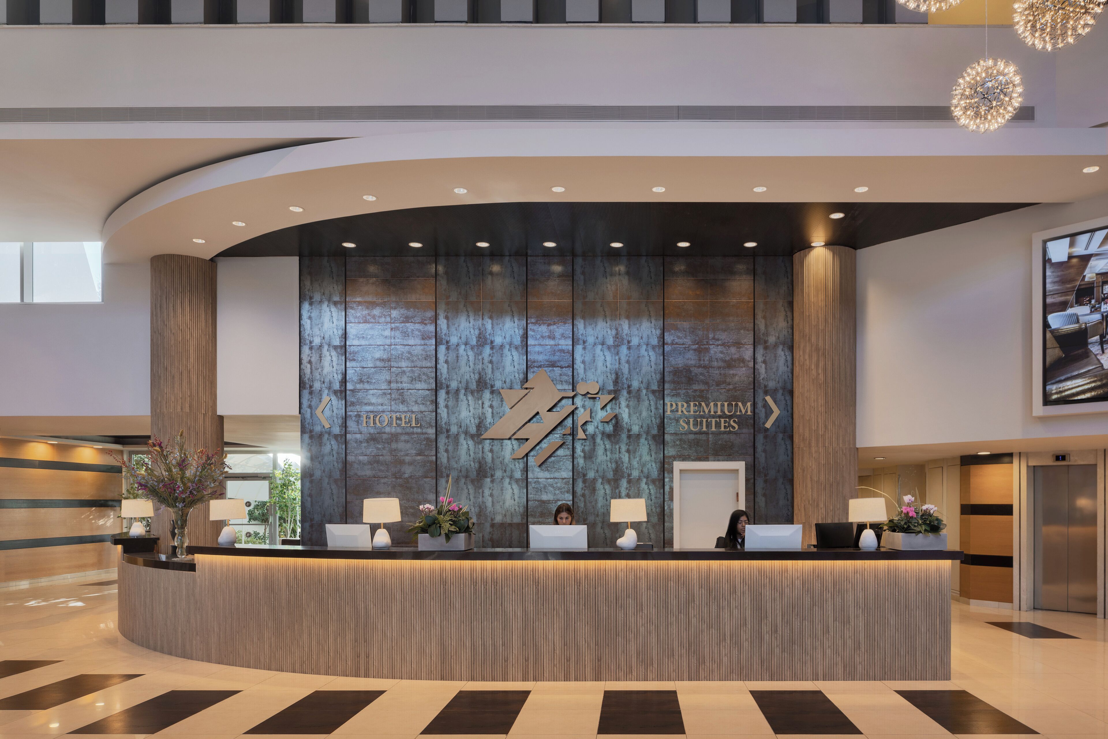 A hotel reception desk with a modern design, featuring a large logo and the words "HOTEL PREMIUM SUITES" on the wall.