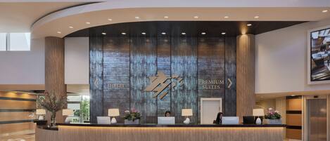 A hotel reception desk with a modern design, featuring a large logo and the words "HOTEL PREMIUM SUITES" on the wall.