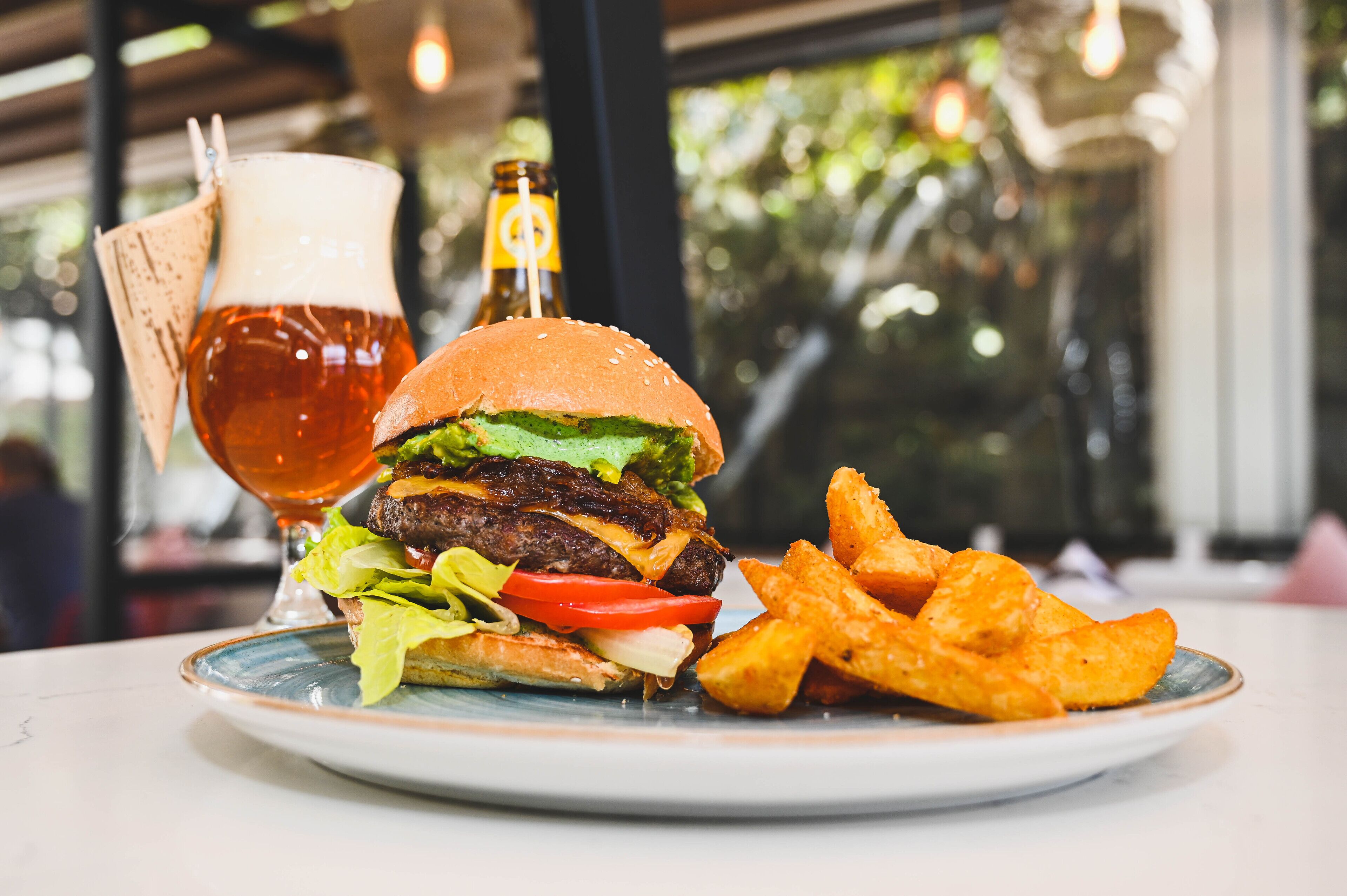 A plate with a burger, fries, and a beer.