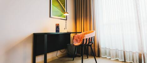 A modern room with a desk, chair, and a framed picture on the wall.