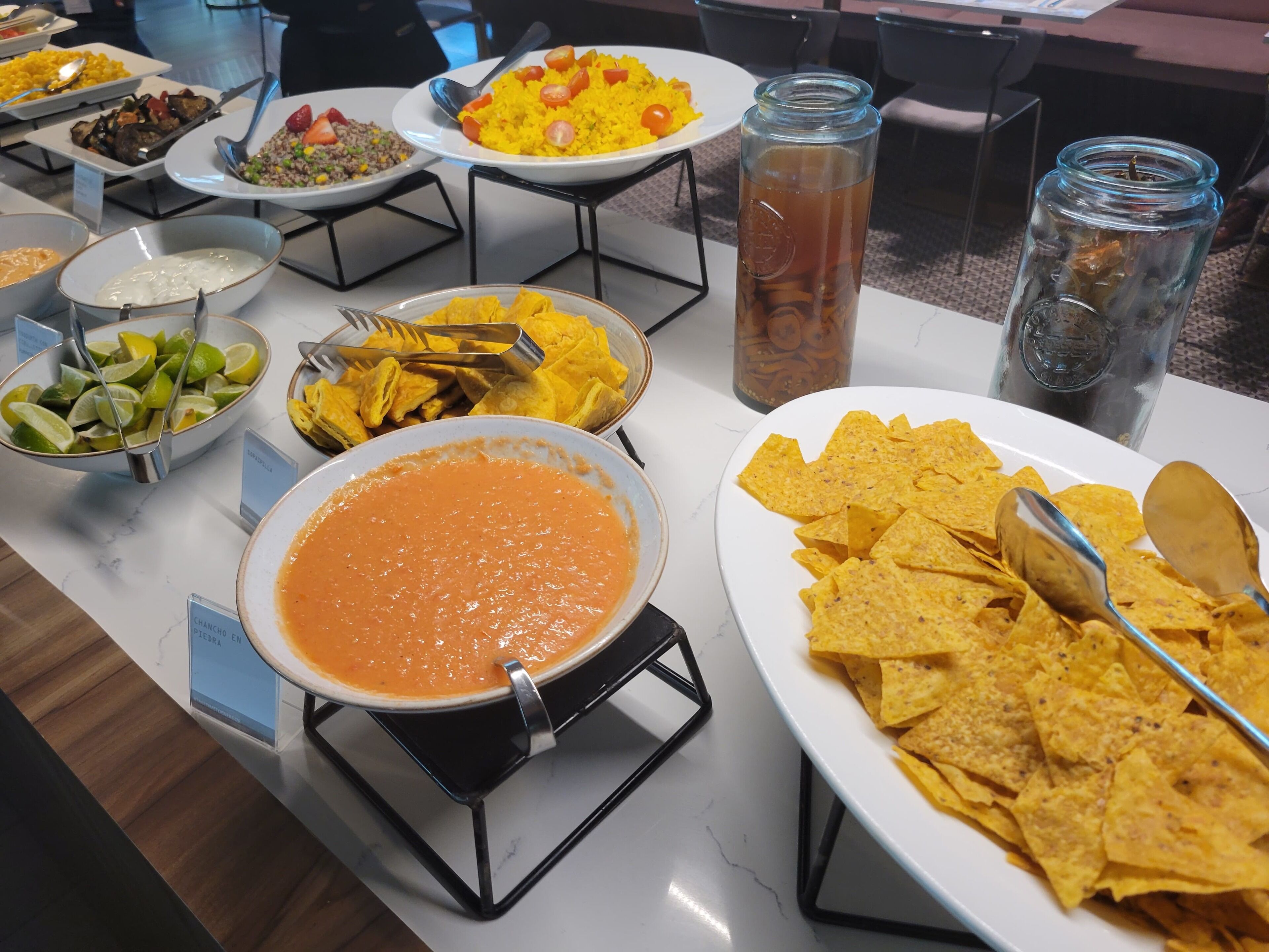 Een buffet met diverse gerechten, waaronder rijst, salade en nachos.