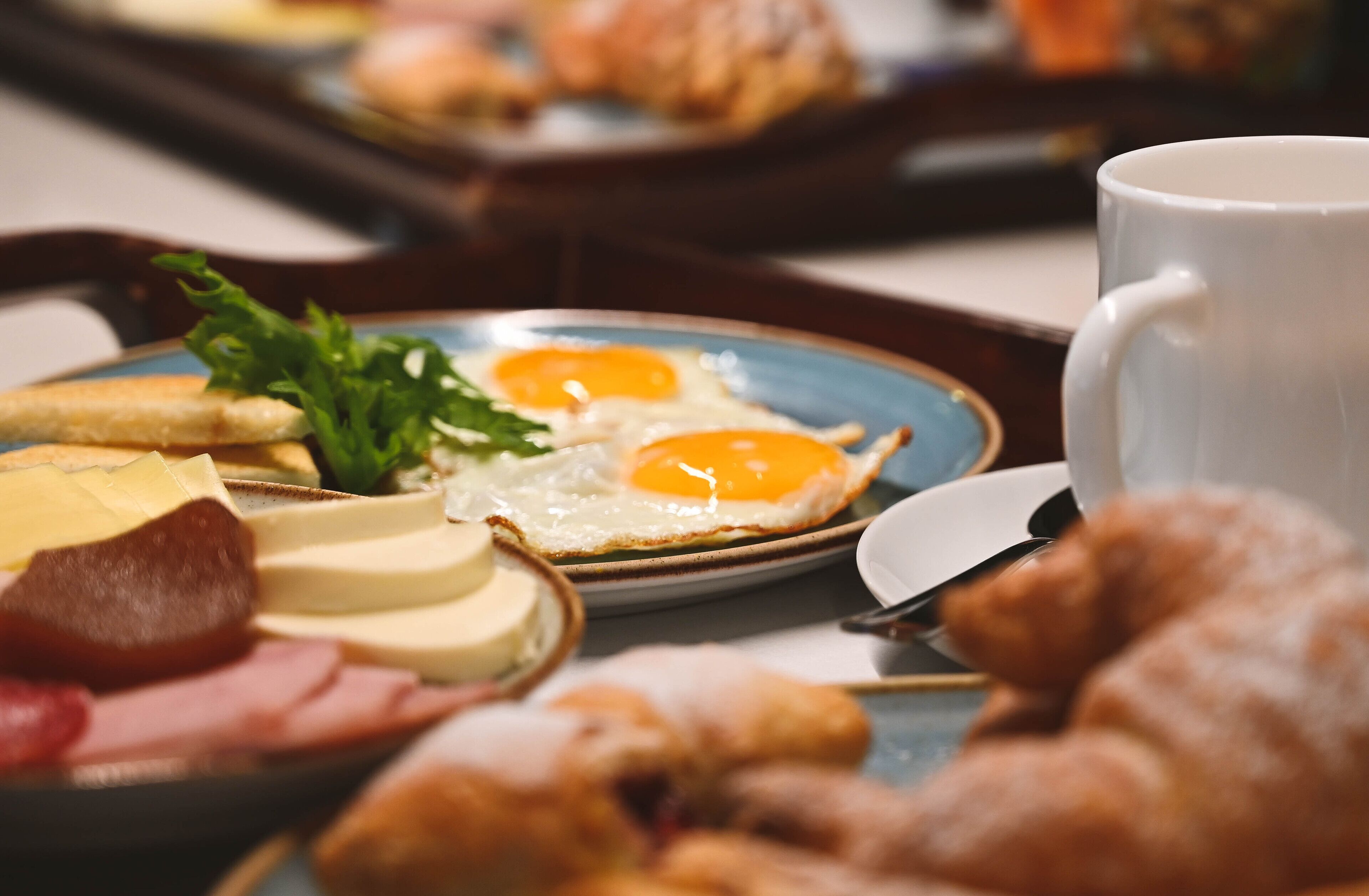 A breakfast tray with eggs, cheese, ham, and croissants.