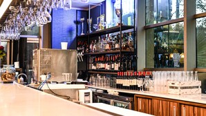 Een bar met flessen drank, glazen en een groot raam met uitzicht.