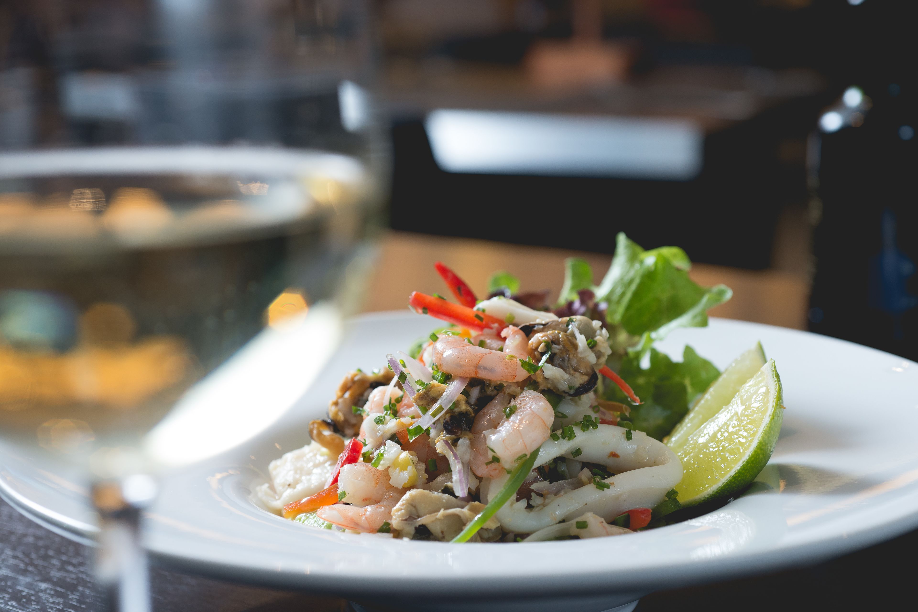 A plate of shrimp salad with a lime wedge, served on a white plate.