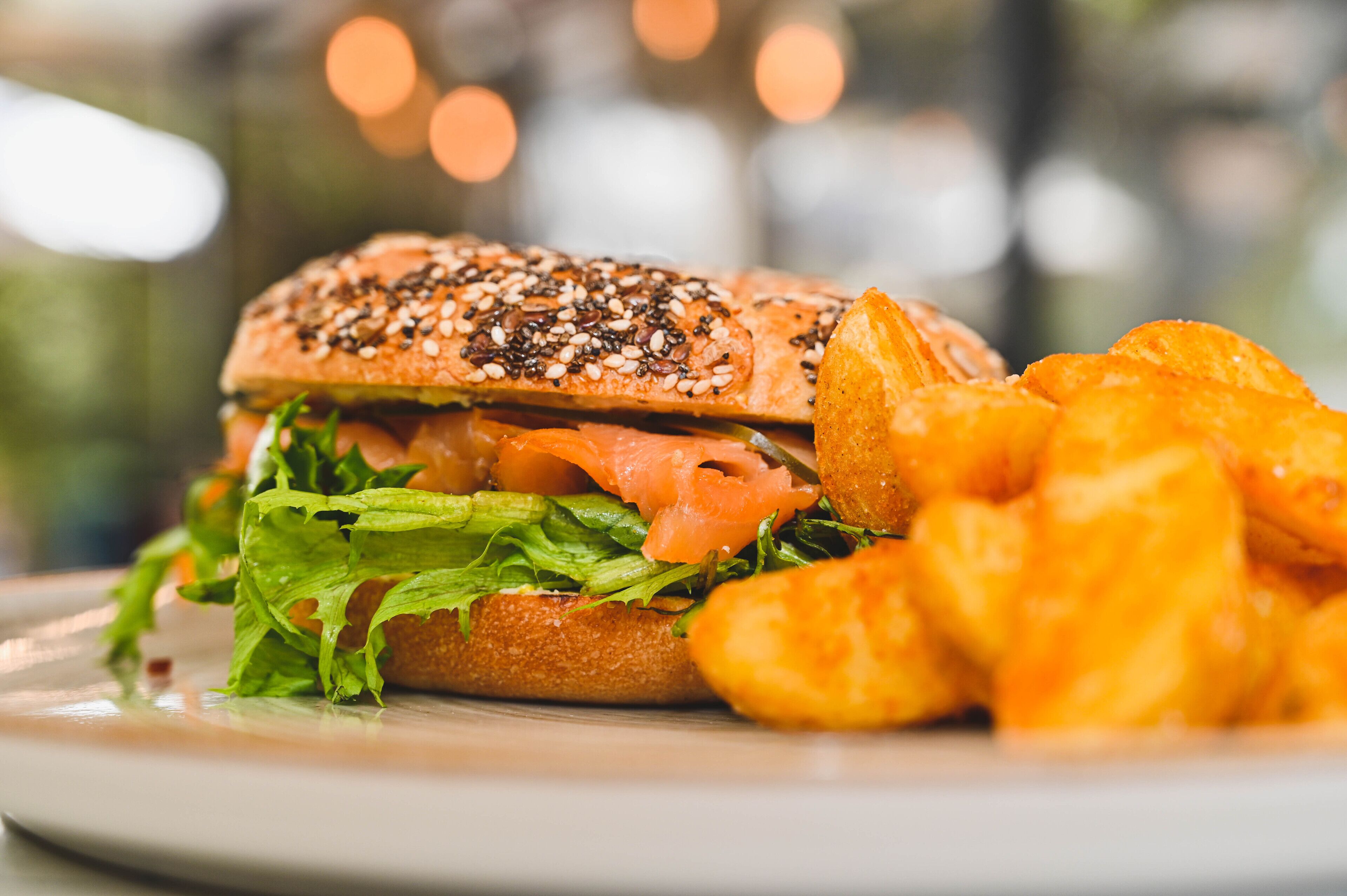 A sandwich with lettuce and a bun, accompanied by a side of potato wedges.