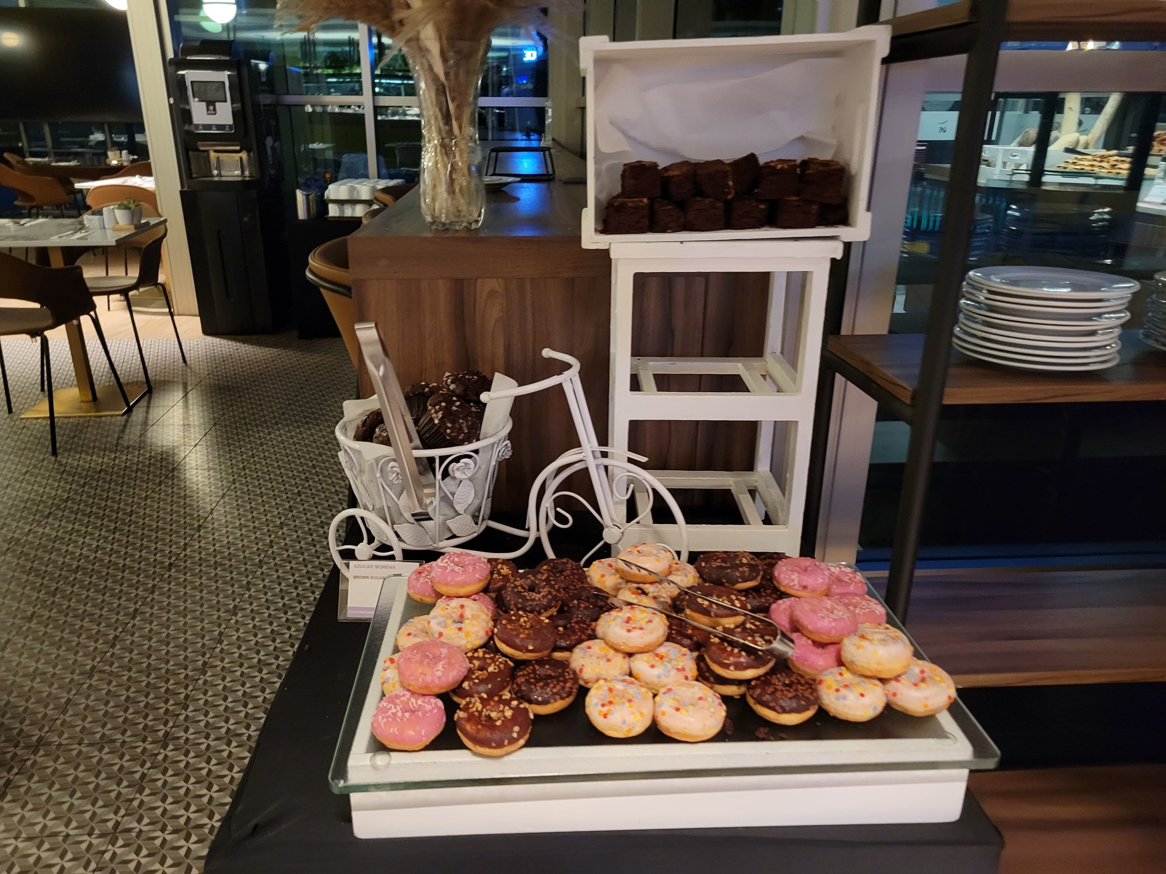 Una exhibición de pasteles y donas en la sección de pastelería de un hotel.