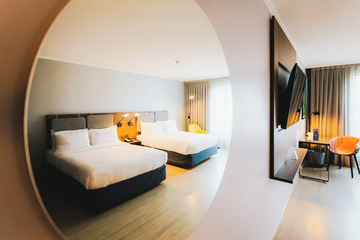 Una habitación de hotel con dos camas, un escritorio, una silla y un televisor.