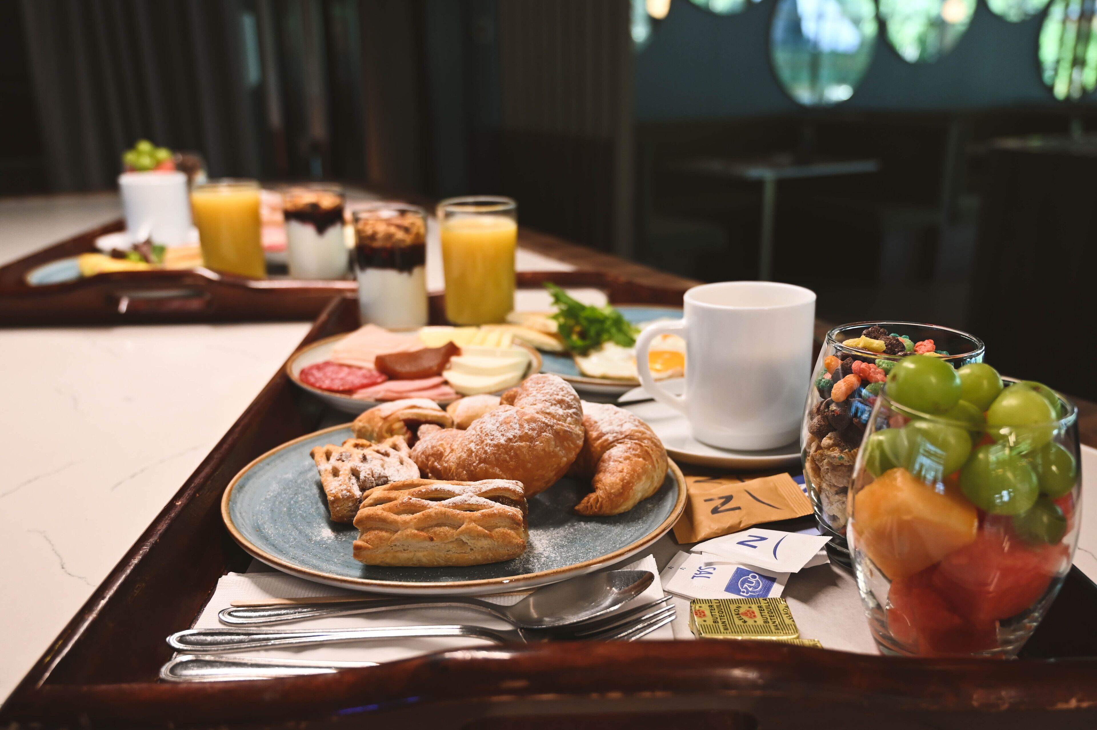 A breakfast tray with pastries, fruits, and beverages.