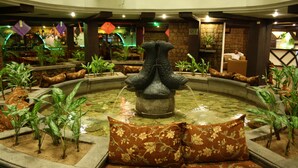 Una fuente circular con una escultura central, rodeada de jardineras y zonas de estar.