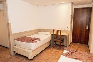 Un dormitorio pequeño y ordenado con una cama individual, un escritorio y una silla.