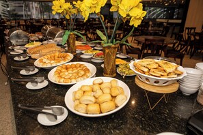 A buffet table with various food items and a vase with yellow flowers.