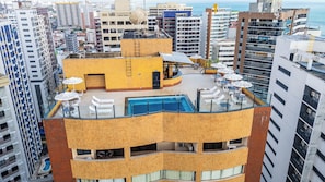 A rooftop pool area with lounge chairs and umbrellas, surrounded by high-rise buildings. - Plaza Praia Suites (Fortaleza)