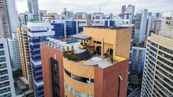 A high-rise building with a rooftop pool and outdoor seating area. - Plaza Praia Suites (Fortaleza)