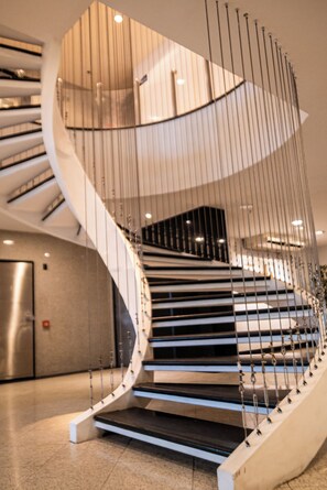 Una escalera espiral moderna con barandillas de metal y protección de vidrio.