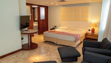 A hotel room with a bed, a TV, a desk, and a seating area.