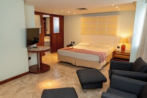 A hotel room with a bed, a TV, a desk, and a seating area.