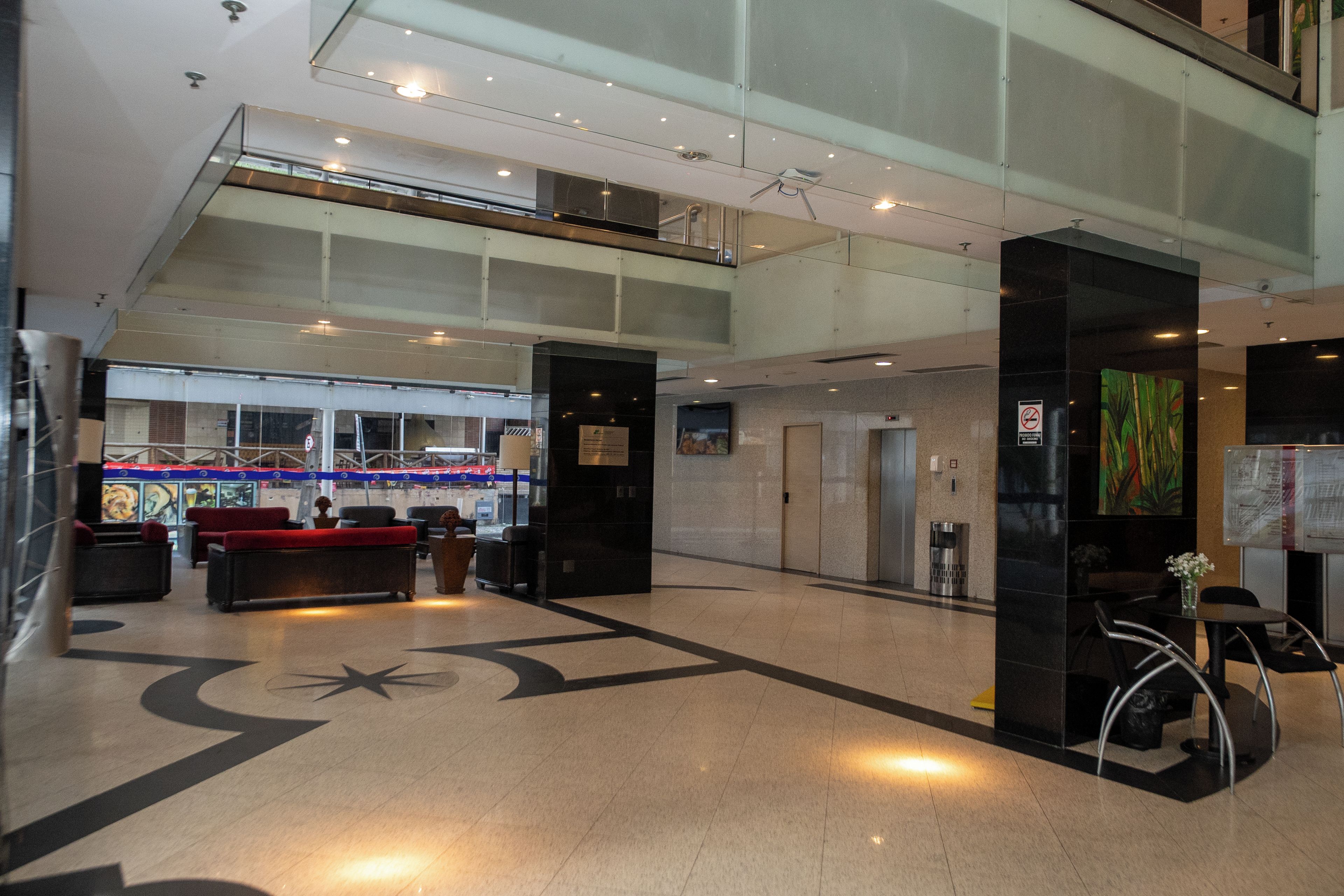 A spacious lobby with a reception desk, seating area, and a large glass window overlooking a street.