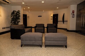 A lobby with seating, a plant, and a fire extinguisher. - Plaza Praia Suites (Fortaleza)