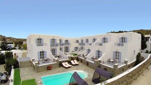 A white building with multiple balconies, a swimming pool, and lounge chairs.