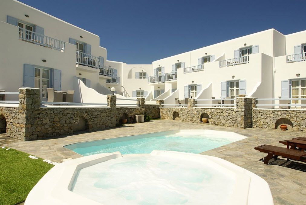 A white building with balconies, a swimming pool, and a hot tub.