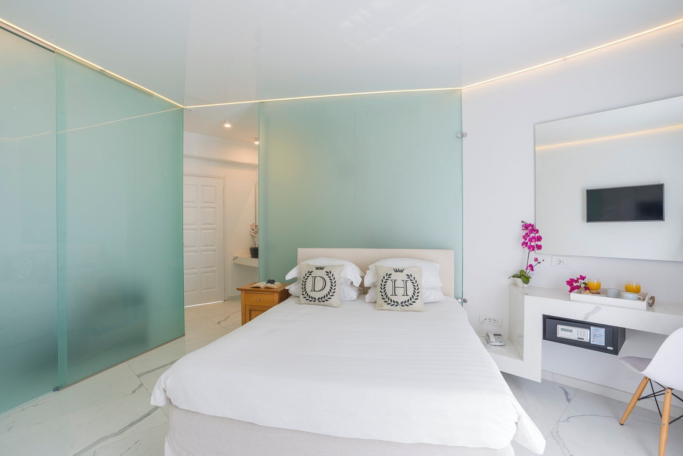 A modern bedroom with a bed, bedside tables, a desk, and a TV.