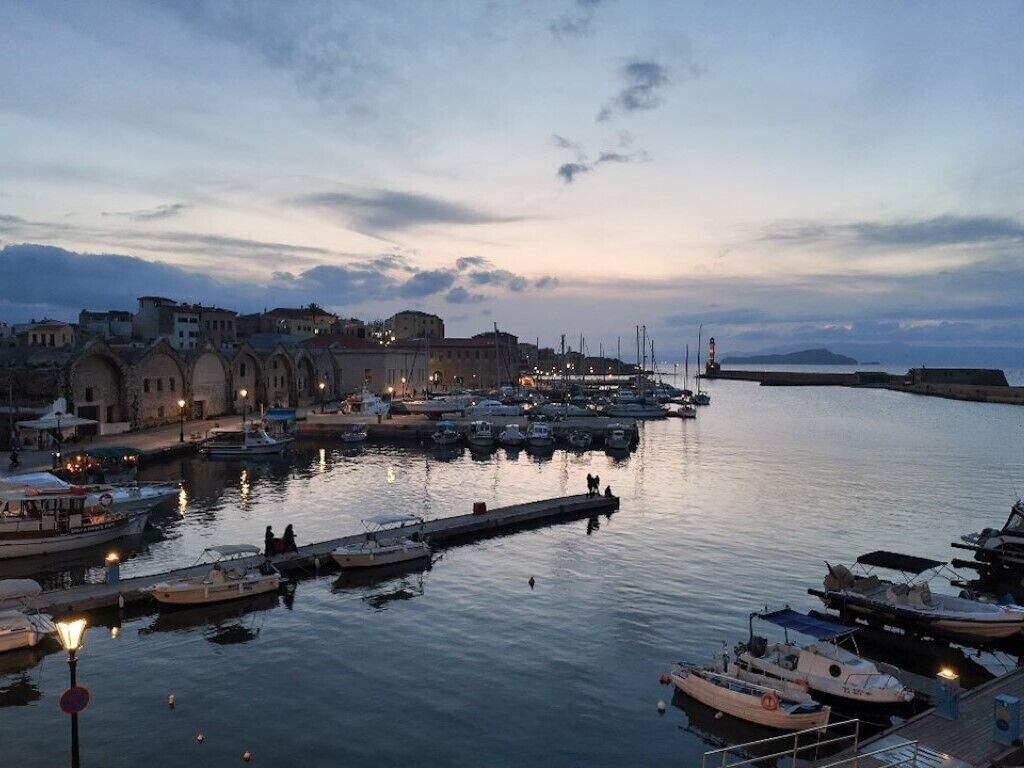 A harbor with boats docked, a pier extending into the water, and buildings along the waterfront.