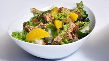 Un tazón de ensalada con hojas verdes mixtas, segmentos de naranja y nueces.