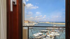 A balcony with a view of a marina, a potted plant, and a door with a handle. - Porto Veneziano Hotel (Chania)