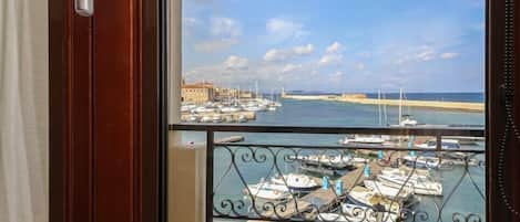 A balcony with a view of a marina, a potted plant, and a door with a handle.
