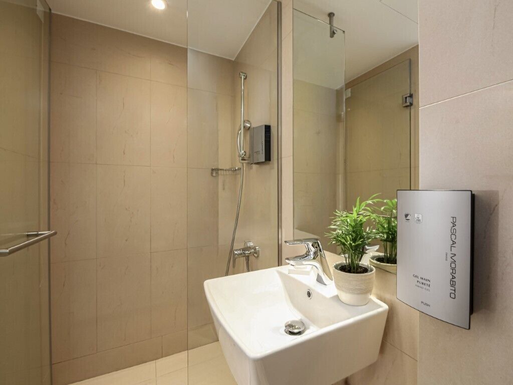 A modern bathroom with a shower, sink, and a mirror.